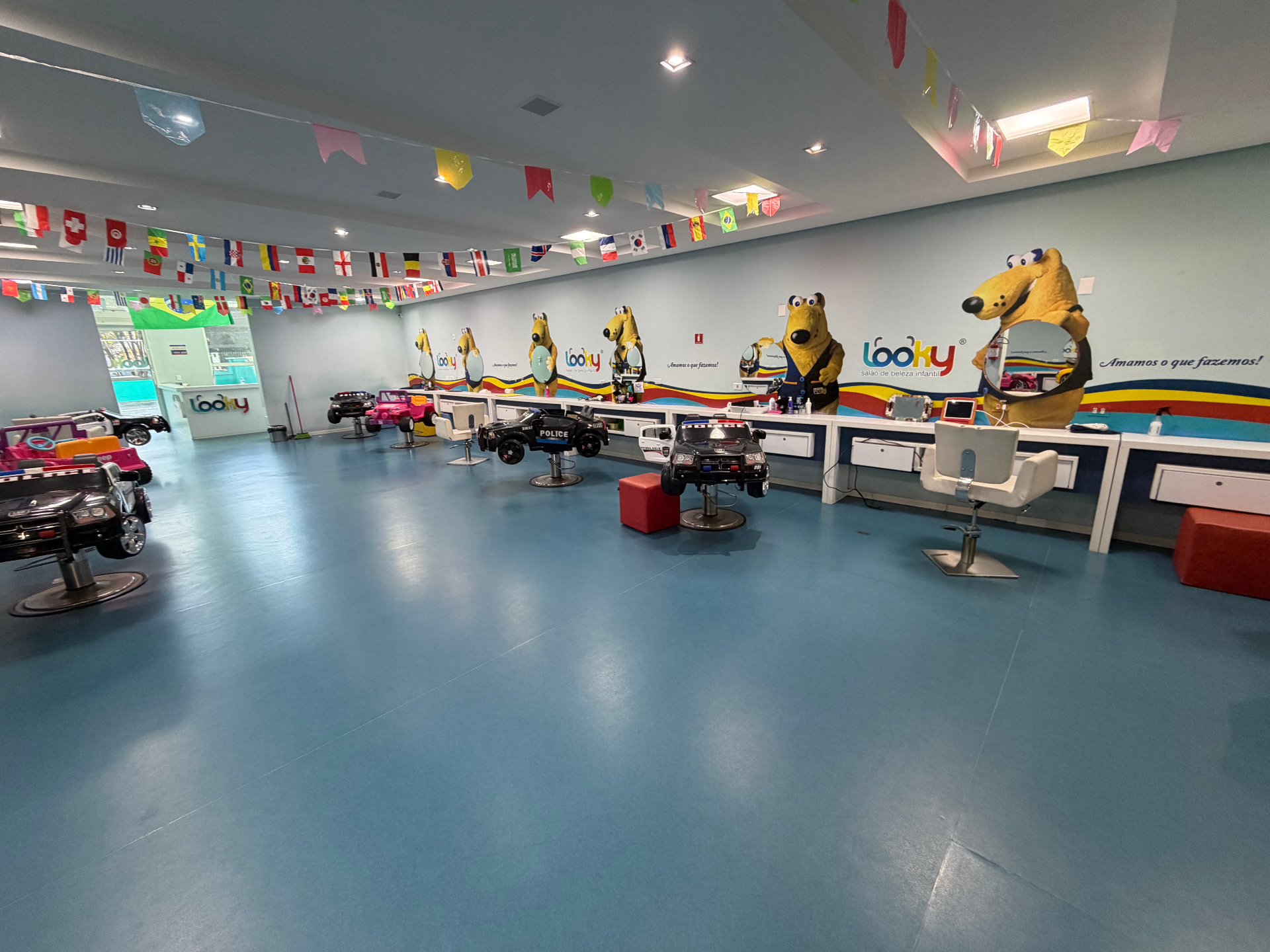 Interior do salão Looky com cadeiras em formato de carrinhos e painel do mascote